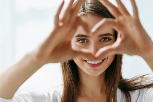 A woman making a heart with her hands.