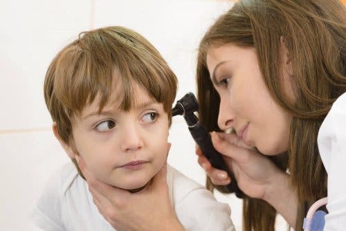 En lege som sjekker et barns ørebetennelse.