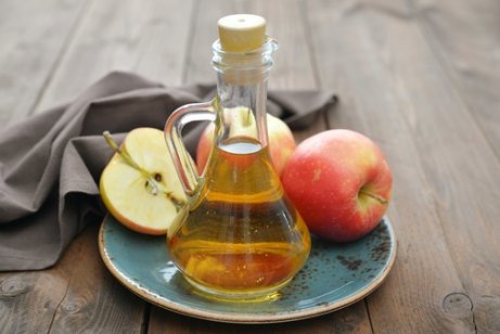 Apple cider in a container next to apples.