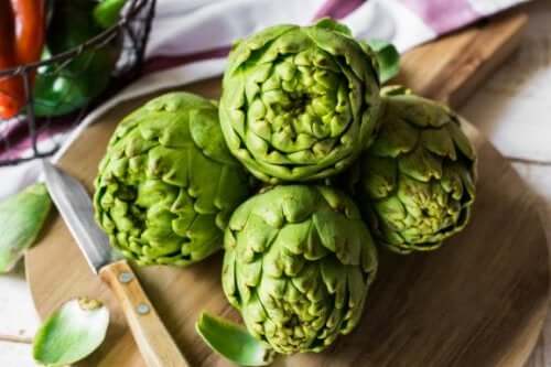 Some artichokes on a cutting board.