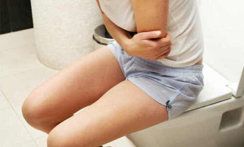 Woman with constipation sitting on the toilet, a benefit of elderberries is to relieve constipation.