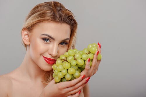 A pretty woman holding a bunch of grapes.