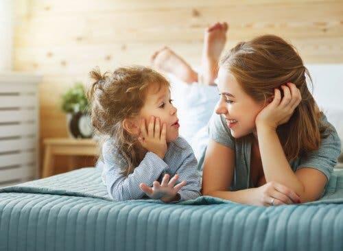 A mom and her kid talking on the bed.