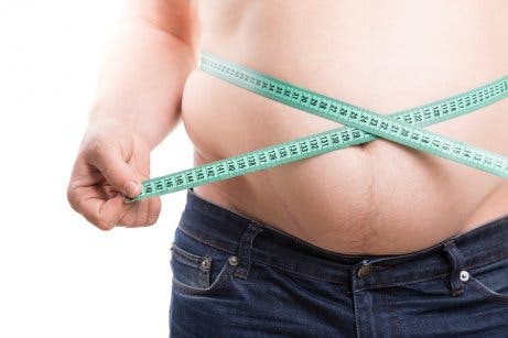Man measuring waist with tape measure.