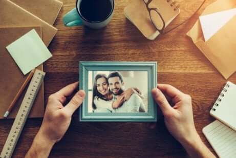 Person holding picture frame over a desk.