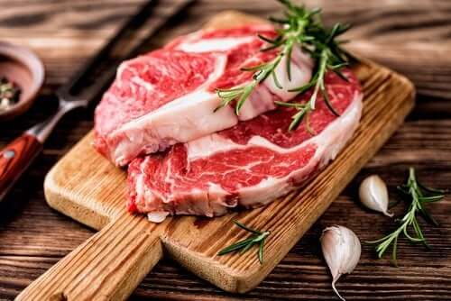 Slices of red meat on a cutting board with garlic and rosemary.