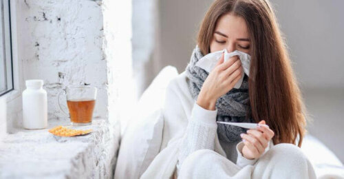 Sick woman checking temperature, one of the benefits of elderberry is relieving cold symptoms.