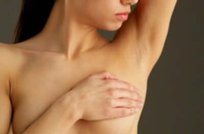 Naked woman raising arm over head.