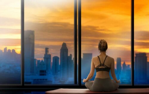 Woman doing yoga looking out at a city skyline as part of the SAVERS method.