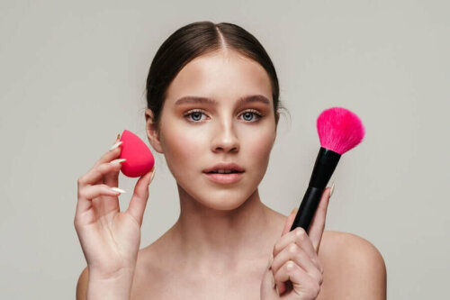 Woman holding makeup brush and sponge.