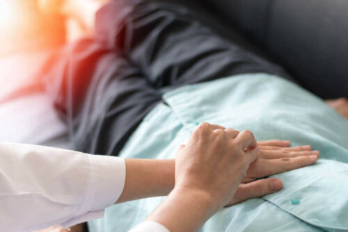 Colon cancer patient laying on couch with doctor's hands on their torso.