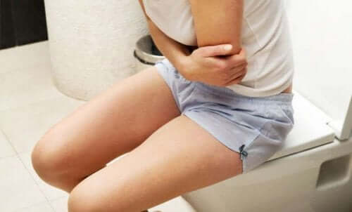 Woman sitting on toilet constipated, holding stomach.