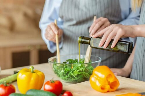 Two people making a salad with ingredients on the counter.