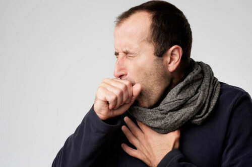 Man wearing a scarf coughing into hand.