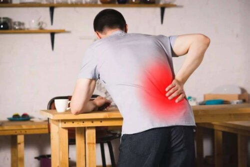 Man leaning on table with back pain.