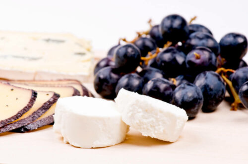 Cheese and grapes on a cutting board.
