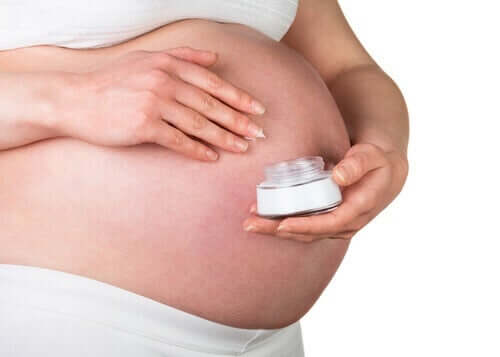 Pregnant woman with a container of skin cream.