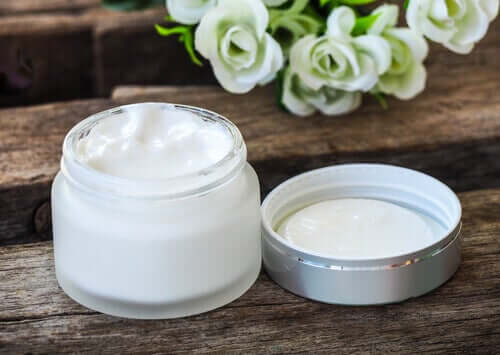 Skin cream in a jar with white roses in the background.