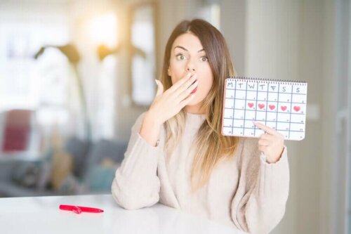 Zaskoczona kobieta trzymająca kalendarz z oznaczeniem jej cyklu miesiączkowego.