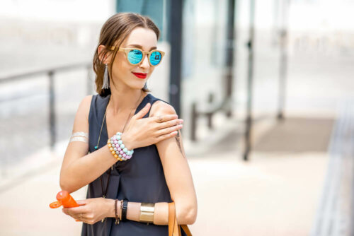 Woman putting sunblock on arm to prevent solar erythema.