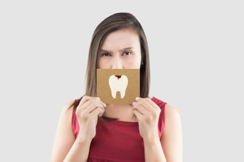 Woman holding a sign with a tooth with a cavity on it in front of her mouth.