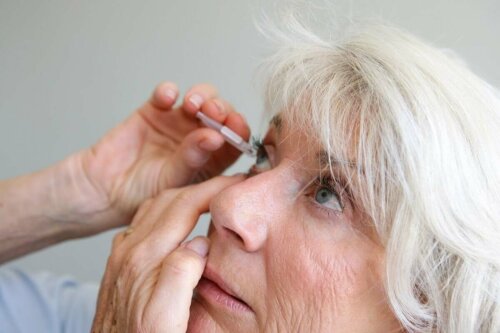 A woman applying drops to her eye.