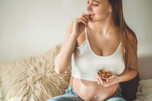 A pregnant woman eating almonds.