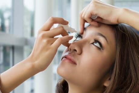 A woman using eye drops.
