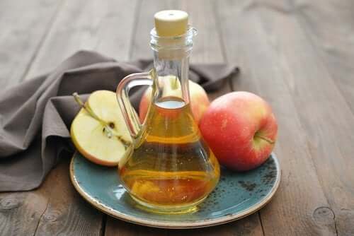 Apple cider vinegar in a jar and fresh apples on a plate.