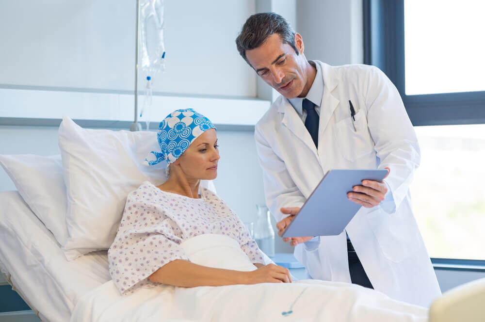 A cancer patient in a hospital bed talking to her doctor.