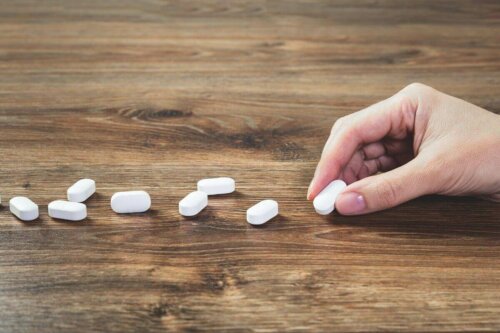 A person putting pills on a table.
