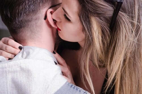A woman biting a man's ear.