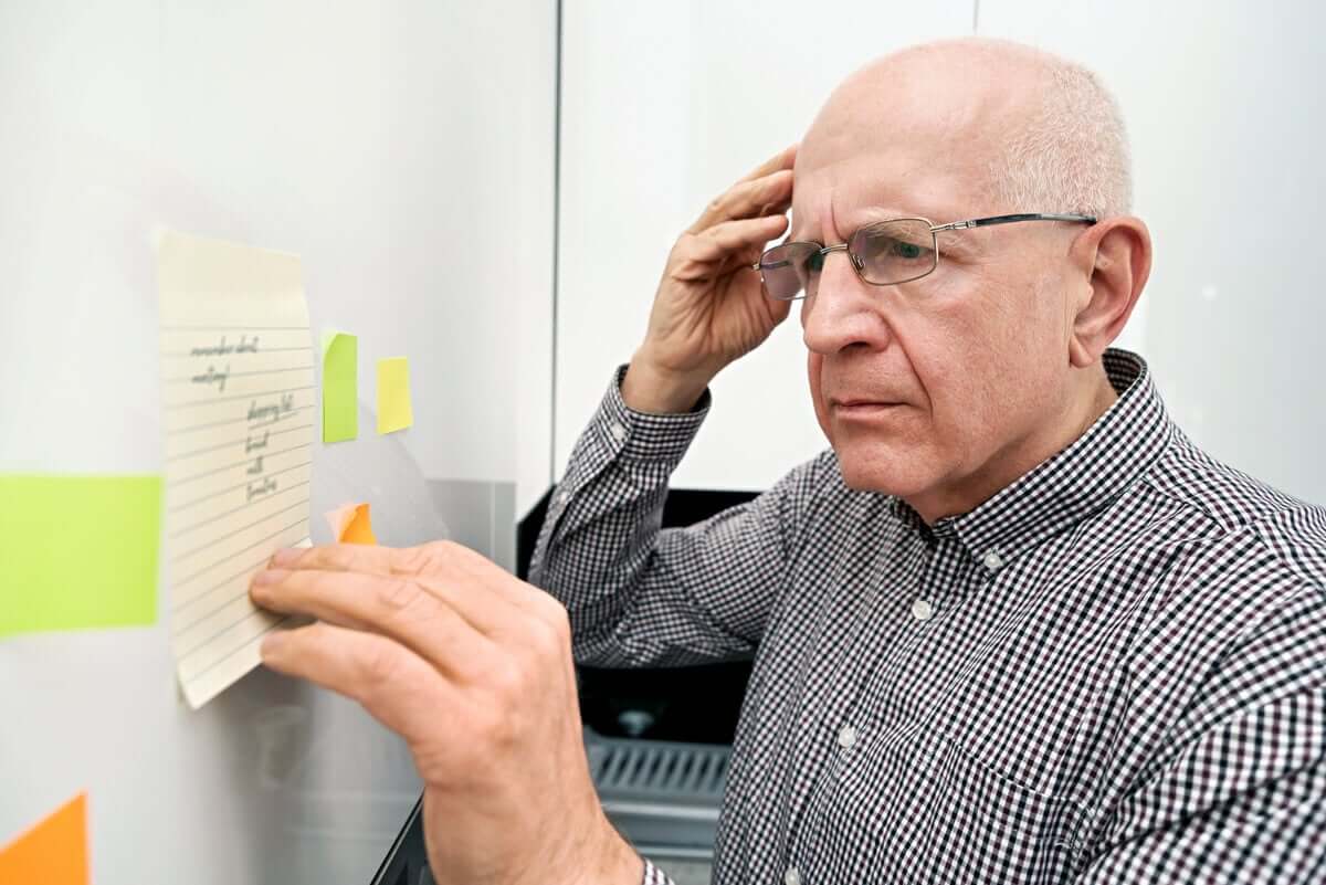 An elderly man looking at a list with a confused expression.