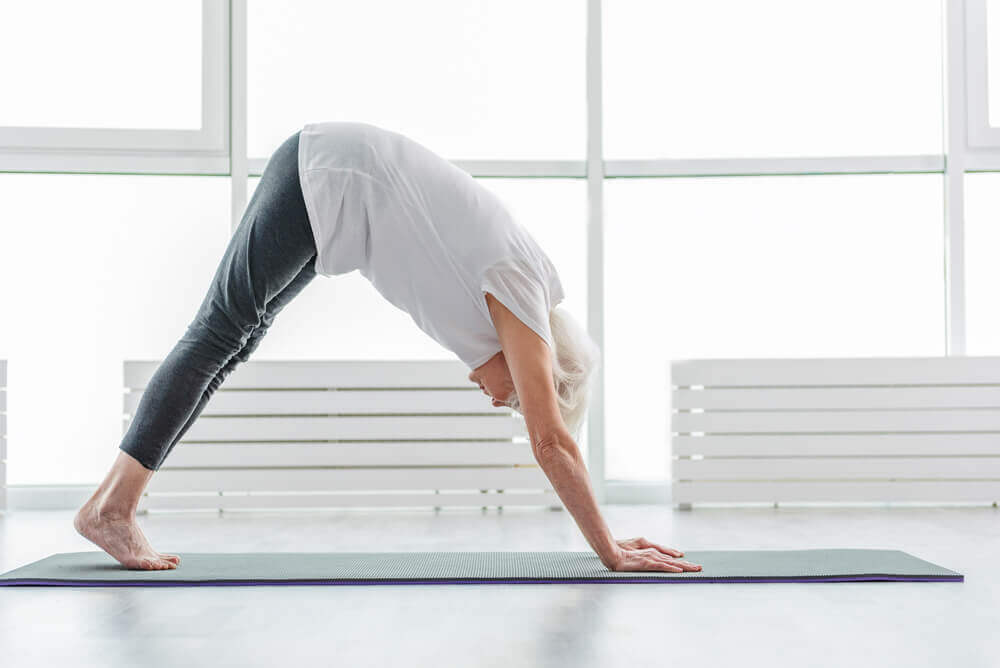 An elderly woman doing yoga.