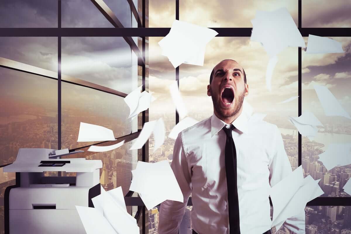 A man having a nervous breakdown at work, throwing papers in the air.