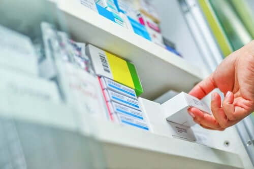 A pharmacist pulling a box of medicine off the shelf.