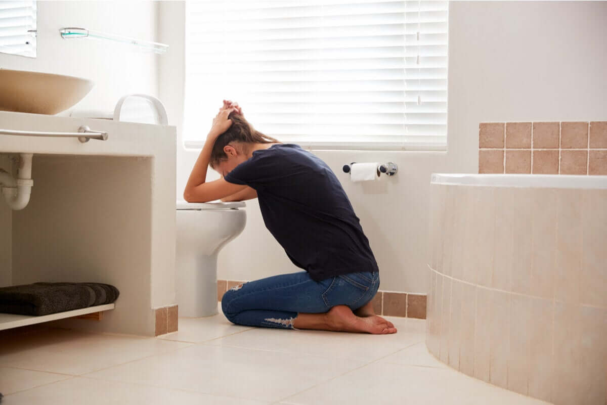 A woman throwing up in the toilet.