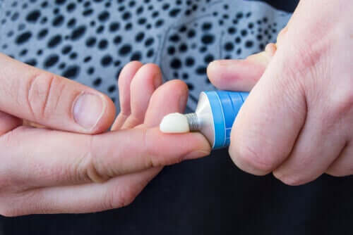 A person squeezing ointment from a tube.