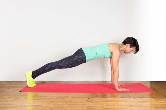 A woman doing a plank on a yoga mat.