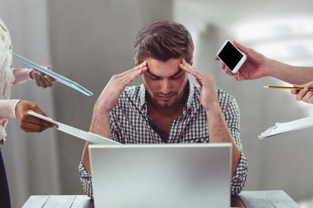A man feeling stressed because of the demands of work.