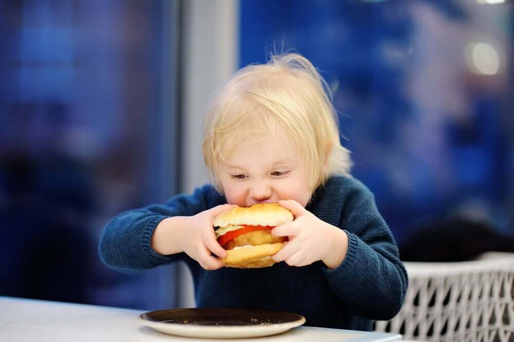 Maluch wgryzający się w hamburgera - nadwaga u dzieci