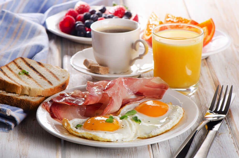 Several plates of breakfast foods, a glass of orange juice, and a cup of coffee.