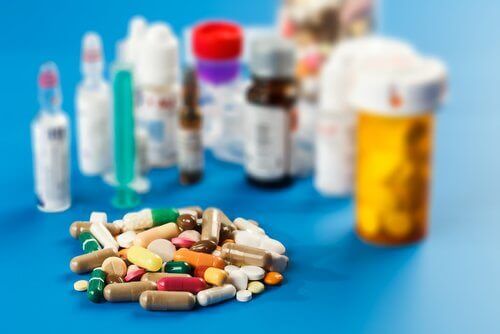 A pile of pills in front of a variety of pill bottles.