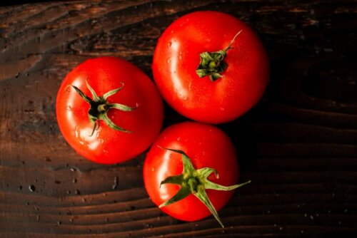 Three tomatoes on a wooden board.