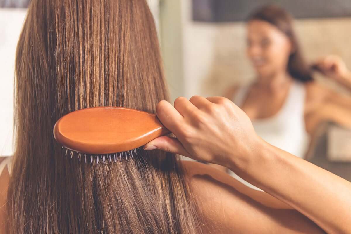 A woman brushing her hair in front of the mirror.
