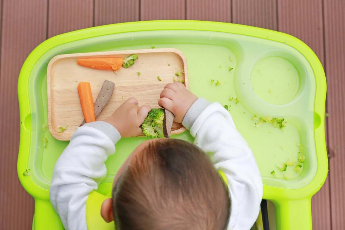 A baby eating vegetables.