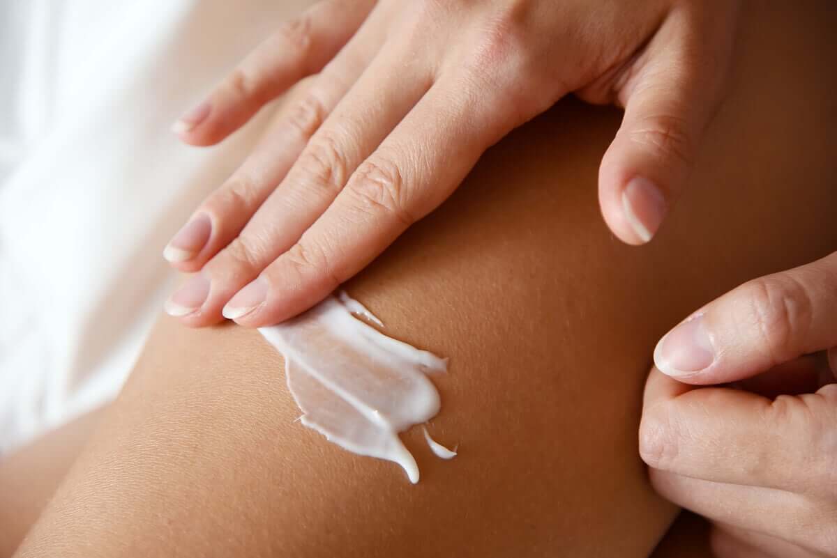 Woman applies lotion to her dry skin.