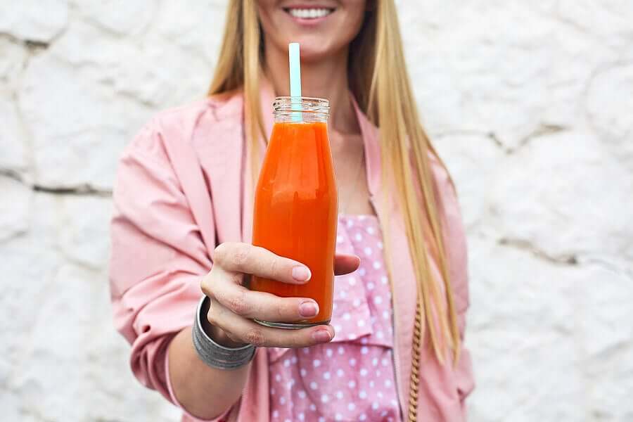 A woman holding a carrot juice.