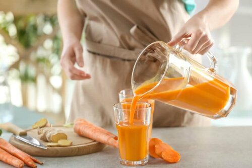 A woman serving a glass of carrot smoothie.