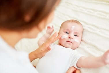 A mother applying cream to a baby's face.